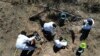FILE - Forensic technicians excavate a field on a plot of land referred to as a cartel "extermination site" where burned human remains are buried, on the outskirts of Nuevo Laredo, Mexico, Feb. 8, 2022.