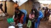 FILE - Members of a family of refugees from the Democratic Republic of Congo sit by their makeshift hut at the Kenani refugee transit camp in Nchelenge, Zambia, Oct. 30, 2017.