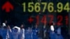 People are reflected in an electronic board outside a Tokyo brokerage. Japan's Nikkei share average rose to an eight-week high.