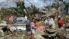 FILE - A typhoon survivor stands on rubbish in Tacloban, central Philippines, Dec. 8, 2013.