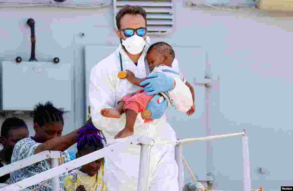 Seorang dokter menggendong bayi imigran yang baru lahir setelah para migran diturunkan dari kapal AL Italia Sirio&nbsp;di pelabuhan Augusta, Sicilia, Italia.