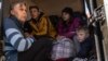 A mother, left, sits in the back of a bus with her children in the town of Bashtanka, after they fled from Snihurivka village, in Ukraine's Mykolaiv region, April 7, 2022, as Russia continues its invasion of Ukraine.