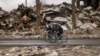 FILE - Men ride bicycles by a destroyed apartment building in Borodyanka, Ukraine, April 6, 2022.