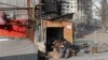 Local residents have a meal outside a building damaged during Russia's invasion of Ukraine, in the besieged southern port city of Mariupol, March 31, 2022. According to U.N. agencies, food supplies are dwindling in Ukraine.