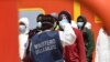 FILE - An Italian health worker takes the temperature of migrants disembarking from a rescue ship on the island of Lampedusa, Italy, May 11, 2021. A new report has found that refugees and migrants have insufficient access to health services in their host countries.