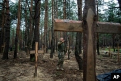 FILE - Oleg Kotenko, the commissioner for issues of missing persons under special circumstances, uses his smartphone to film the unidentified graves of civilians and Ukrainian soldiers in the recently retaken area of Izium, Ukraine, Sept. 15, 2022.