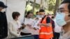A staff member assists people waiting in line outside a coronavirus disease (COVID-19) vaccination center at Sydney Olympic Park during a lockdown to curb the spread of an outbreak in Sydney, Australia, Aug. 16, 2021. 