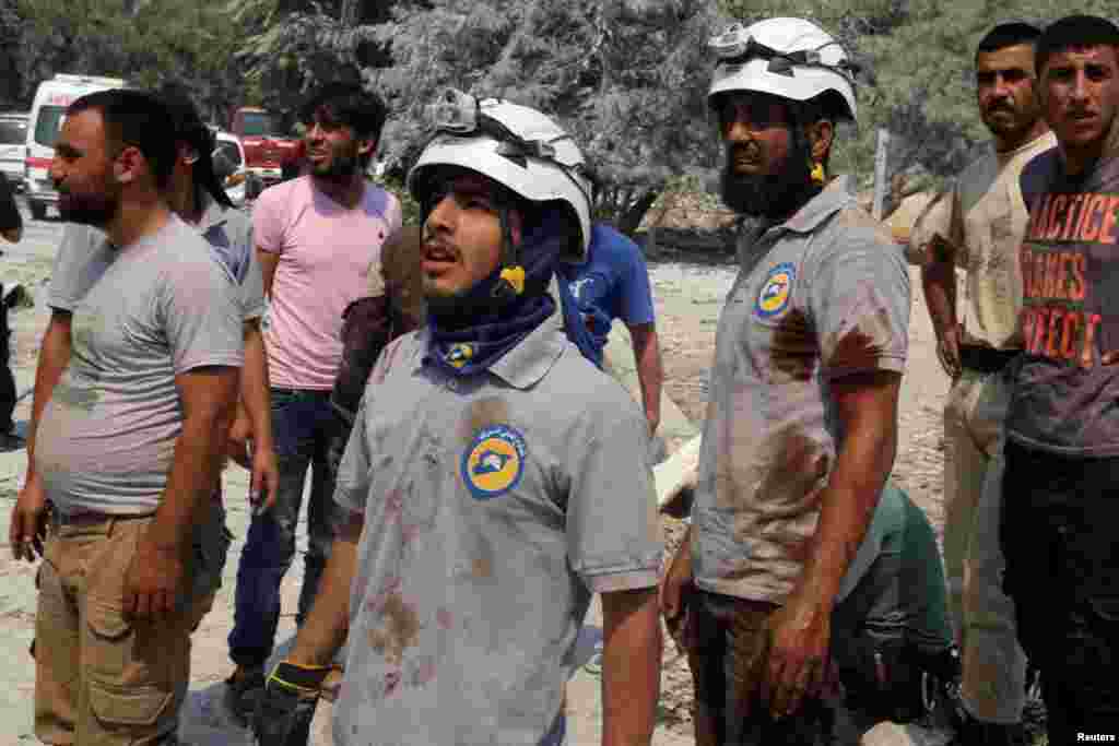 Para anggota Pertahanan Sipil dengan baju bernoda darah di lokasi serangan udara di Bab al-Nairab, Aleppo (27/8).&nbsp;(Reuters/Abdalrhman Ismail)