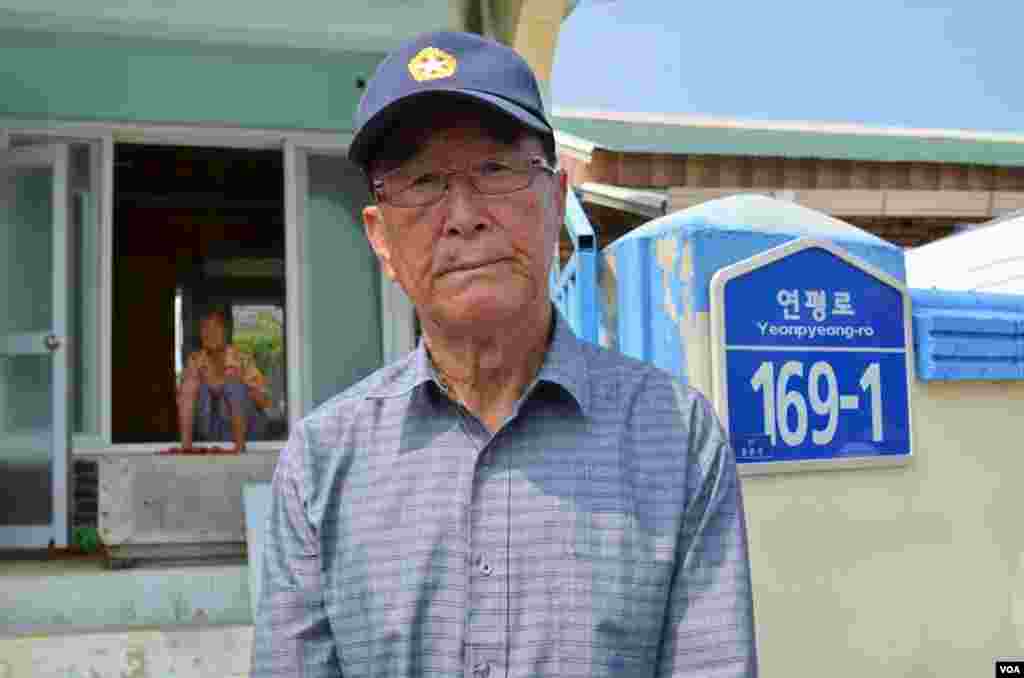 Kim Yoo-sung, 84, at the gate of his home that was severely damaged by the North Korean artillery attack. (Photo: VOA / Steve Herman)