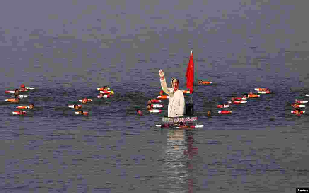 Participants swim together with a portrait of late Chinese Chairman Mao Zedong in the Hanjiang River, a large branch of the Yangtze River in Xiangyang, in Hubei province, July 13, 2014, to celebrate the upcoming 48th anniversary of Mao swimming in the Yangtze River on July 16, 1966, local media reported.