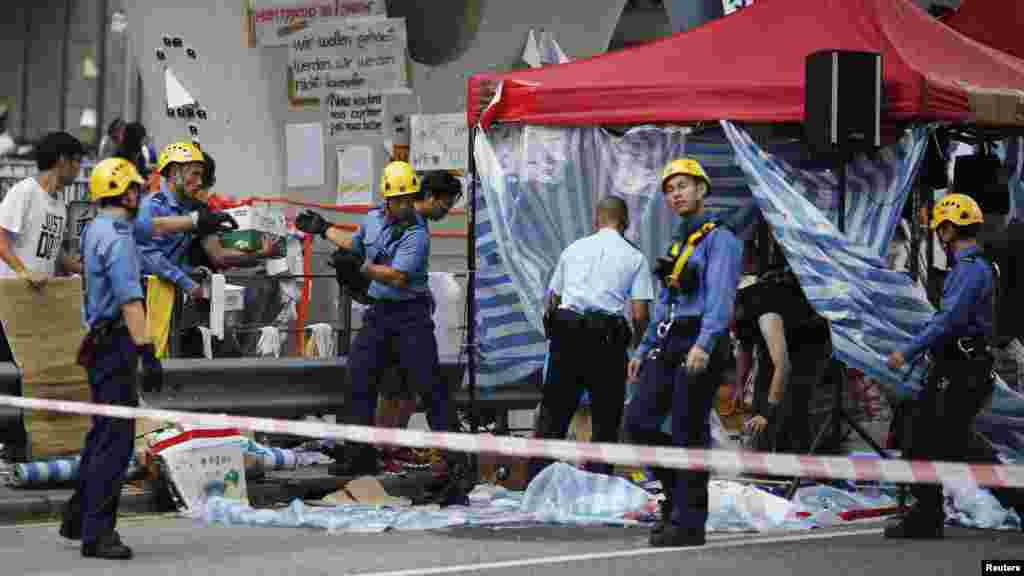 Petugas pemadam kebakaran memindahkan tenda di bawah jembatan penyeberang jalan dekat kantor-kantor pemerintahan di Hong Kong (5/10). (Reuters/Carlos Barria)