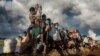 FILE - Rohingya refugees fleeing Myanmar cross a muddy rice field in Palang Khali, Bangladesh, in October 2017. (IWMF/Paula Bronstein)