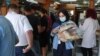 People queue as a woman carries several loafs of bread at a bakery in Beirut, Lebanon, June 29, 2022.
