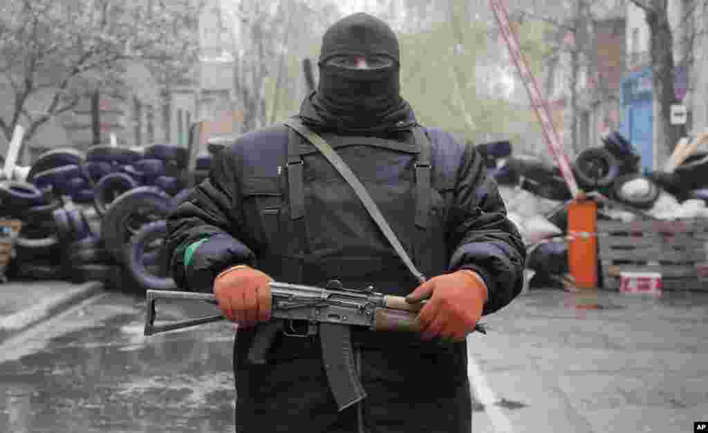 Seorang pria bersenjata pro-Rusia berjaga-jaga di depan kantor polisi yang diduduki militan pro-Rusia di kota Slovyansk, Ukraina timur (13/4).&nbsp;(AP/Efrem Lukatsky)