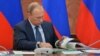 FILE - Russian President Vladimir Putin looks through a book during meeting with senior government officials in Magas, regional Ingushetian capital, Russia, Sept. 13, 2015.