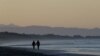 FILE - A couple walk along New Brighton Beach in Christchurch, New Zealand, June 9, 2020. Then-Health Minister David Clark was heavily criticized for ignoring lockdown and taking his family to a beach. He has since resigned.
