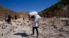 People carry belongings as they cross into Syria on foot, through a crater caused by Israeli airstrikes aiming to block Beirut-Damascus highway at the Masnaa crossing, in the eastern Bekaa Valley, Lebanon, Oct. 5, 2024.