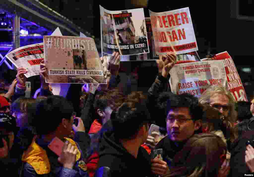 Protesters hold up posters to protest against Turkish President Tayyip Erdogan during the red carpet arrivals at the opening gala of the 66th Berlinale International Film Festival, in Berlin, Germany.