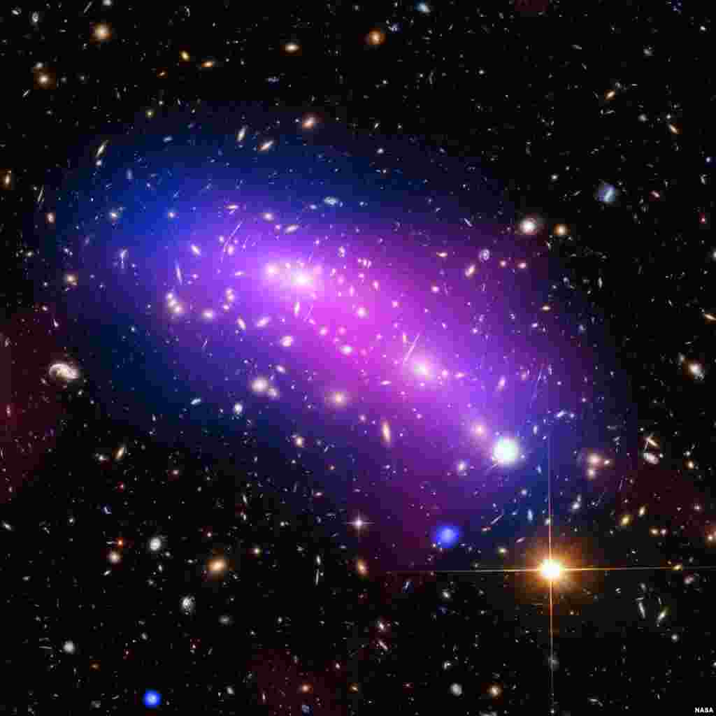 A multi-colored haze, which marks the site of two colliding galaxy clusters forming a single object known as MACS J0416.1-2403, is seen in an undated NASA image which combines data from three different telescopes: the NASA/ESA Hubble Space Telescope (showing the galaxies and stars), the NASA Chandra X-ray Observatory (diffuse emission in blue), and the NRAO Jansky Very Large Array (diffuse emission in pink).