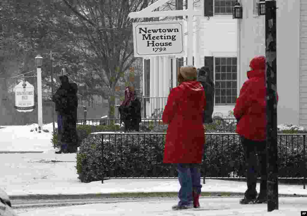 People pause in silence while church bells ring in honor of the victims of the Sandy Hook massacre, Newtown, Conn., Dec. 14, 2013.
