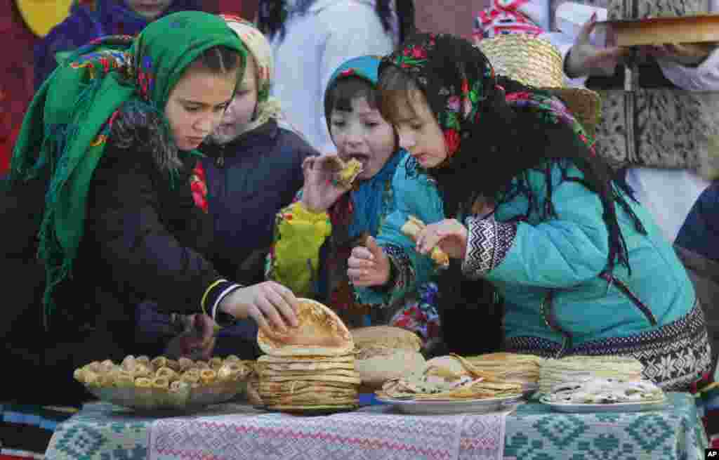Belarusian children eat pancakes during Maslenitsa celebrations, or Shrovetide, in the village of Otradnoye, 150 km (93 miles) south of Minsk, Belarus.