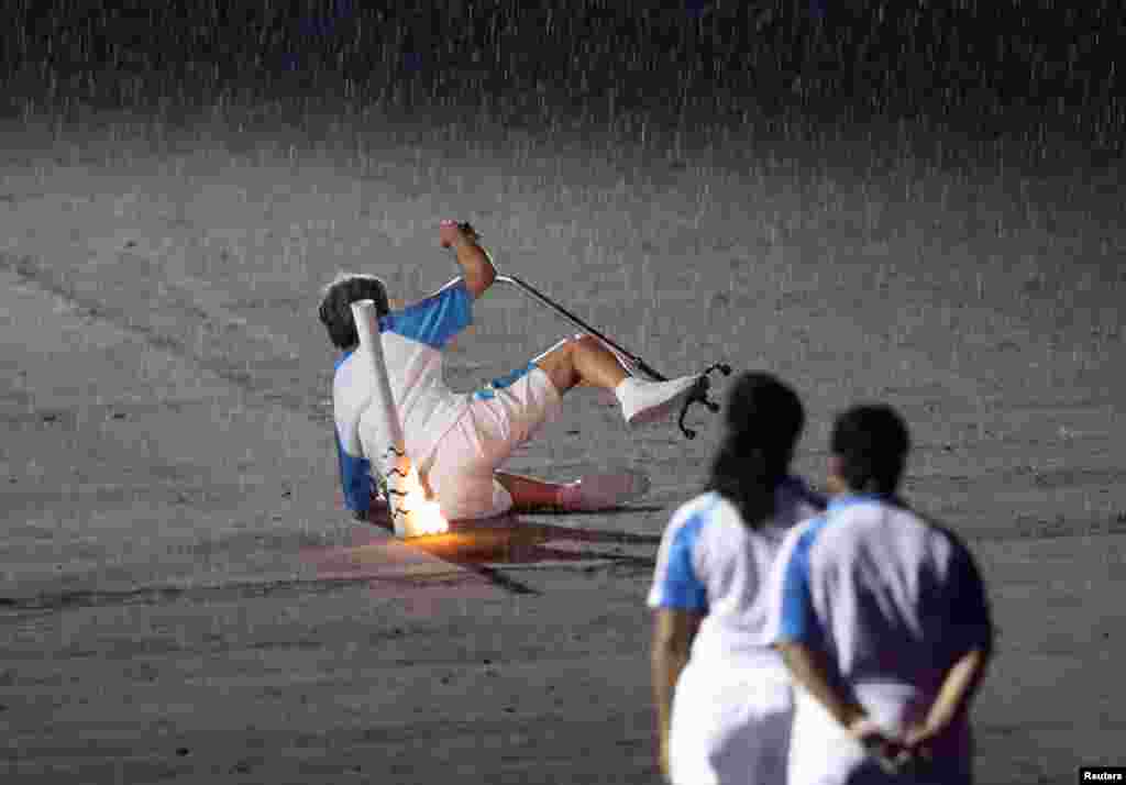 Pelari Paralimpiade Brazil, Marcia Malsar, terjatuh saat membawa Obor Paralimpiade Rio 2016 saat hujan turun di stadion Maracana, Rio de Janeiro, Brazil.