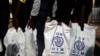 FILE - Gambian migrants repatriated from Libya stand in line with plastic bag from the International Organization for Migration (IOM) as they wait to be registered at the airport in Banjul, Gambia, April 4, 2017.