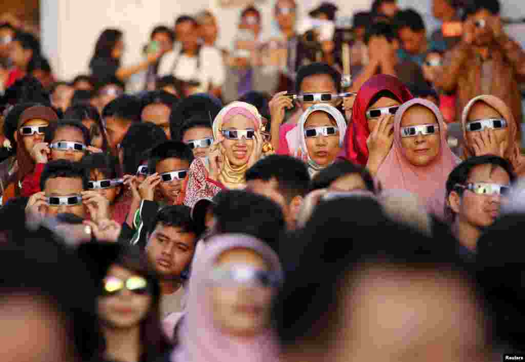 People watch a solar eclipse outside the planetarium in Jakarta, Indonesia.