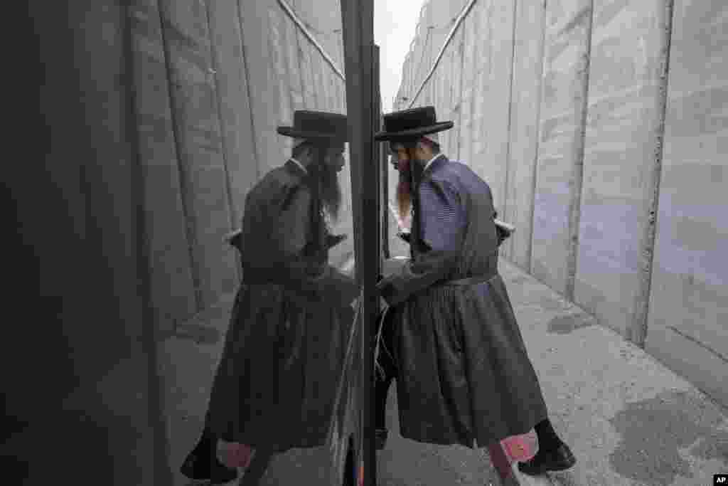An Ultra Orthodox Jewish man gets on a bus near by the concrete barrier built by Israel to secure the Rachel&#39;s Tomb Judaism&#39;s third holiest shrine, during an annual mass prayer that drew tens of thousands of worshippers to commemorate the Jewish Matriarch Rachel, in the west bank town of Bethlehem.