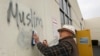 Tom Garing cleans up racist graffiti painted on the side of a mosque in what officials are calling an apparent hate crime, Feb. 1, 2017, in Roseville, Calif. The Tarbiya Institute was spray-painted with a dozen obscene and racist slurs. Garing, a retiree 