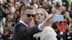 FILE - Director Nicolas Winding Refn and actress Elle Fanning pose for a selfie photograph during a photo call for the film The Neon Demon at the 69th international film festival, Cannes, southern France, Friday, May 20, 2016.
