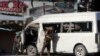 An Afghan security forces member inspects a bus carrying local TV station employees that hit a roadside bomb in Kabul, Afghanistan, Saturday, May 30, 2020. 