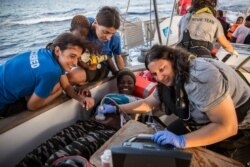 Doctors tend to a pregnant woman on a Mediterranea Saving Humans NGO boat, as they sail off Italy's southernmost island of Lampedusa, just outside Italian territorial waters, July 4, 2019.