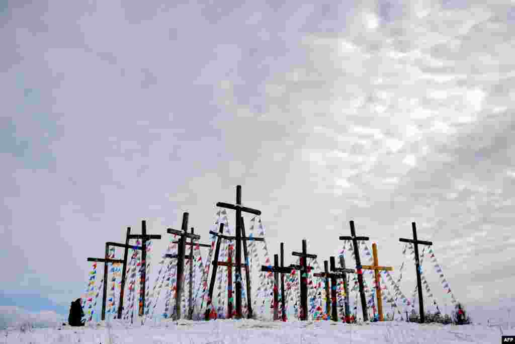 A woman prays on a hill with wooden crosses as she celebrates Palm Sunday in the town of Oshmiany, some 130 kilometers northwest of Minsk, Belarus.