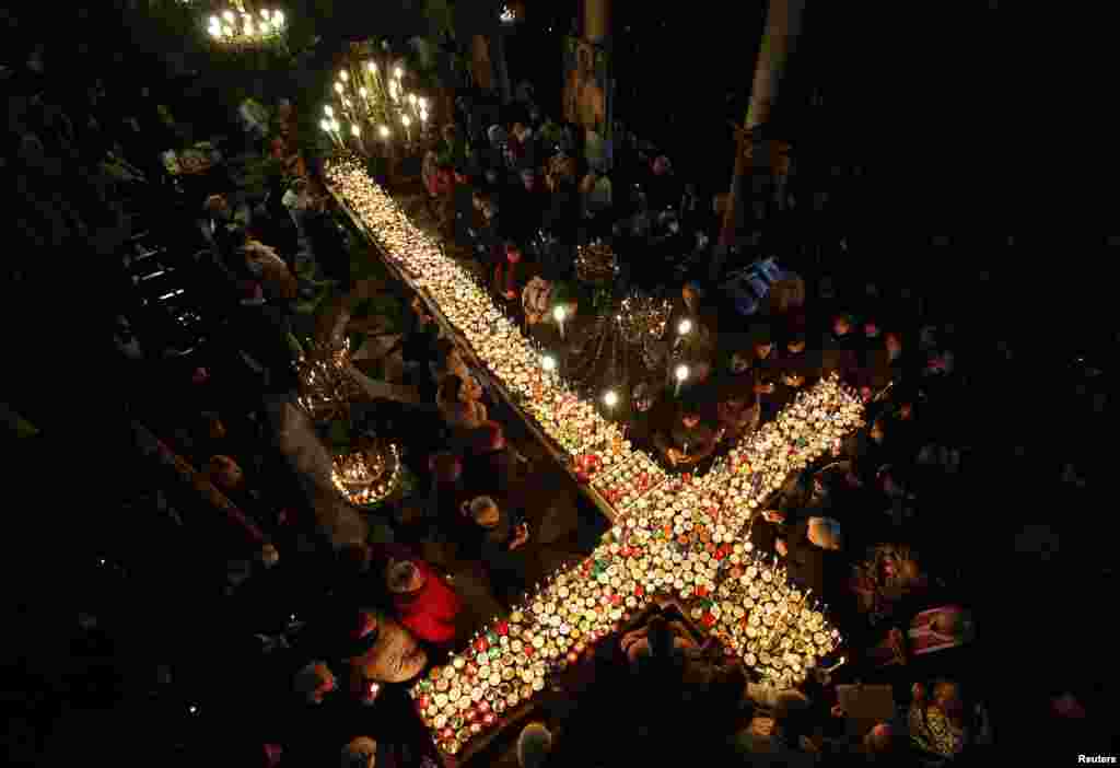 Worshipers gather around candles stuck to jars with honey, arranged in the form of a cross, during a Mass in the church of the Presentation of the Blessed Virgin in Blagoevgrad, Bulgaria.