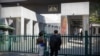 FILE - People stand at the gates of the Australian Embassy in Beijing, Sept. 1, 2020. 