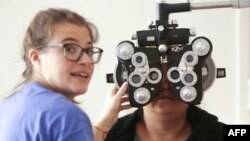 FILE - A woman gets an eye exam during a clinic at Key Arena, in Seattle, Washington, Oct. 28, 2016.