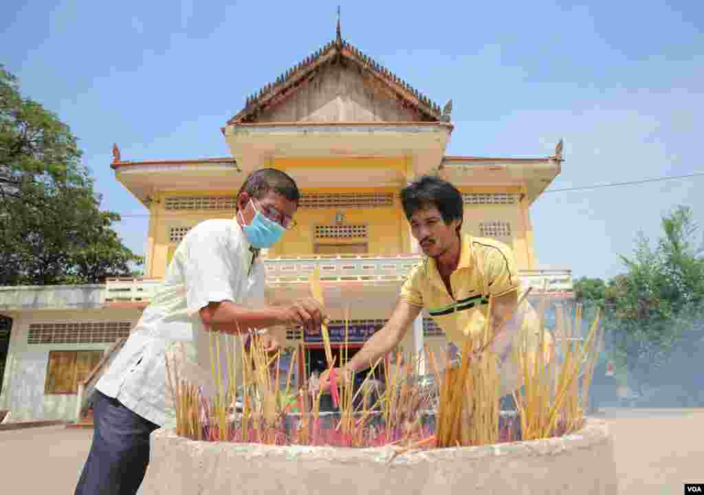 បុរស​ពីរ​នាក់​កំពុង​អុជ​ធូប​នៅ​វត្ត​និរោធ​រង្សី រាជធានី​ភ្នំពេញ ក្នុង​អំឡុង​​ពេល​​ប្រារព្ធ​ពិធី​បុណ្យ​ចូល​ឆ្នាំ​ខ្មែរ​ថ្ងៃទី​២ នៅ​ថ្ងៃ​ទី​១៤ ខែមេសា ឆ្នាំ​២០២០។ (កាន់ វិច្ឆិកា/VOA)
