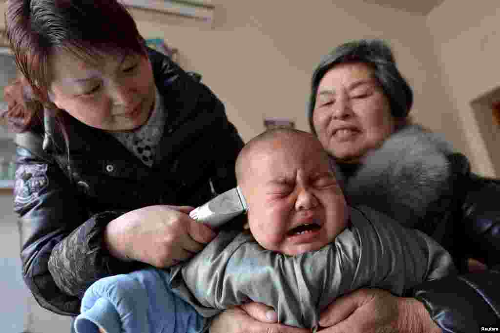 A child cries during a haircut in a barbershop during the Longtaitou (which means the dragon raises its head) Festival, on the second day of the second month of Chinese Lunar calendar, in Baokang County, Hubei Province, China.