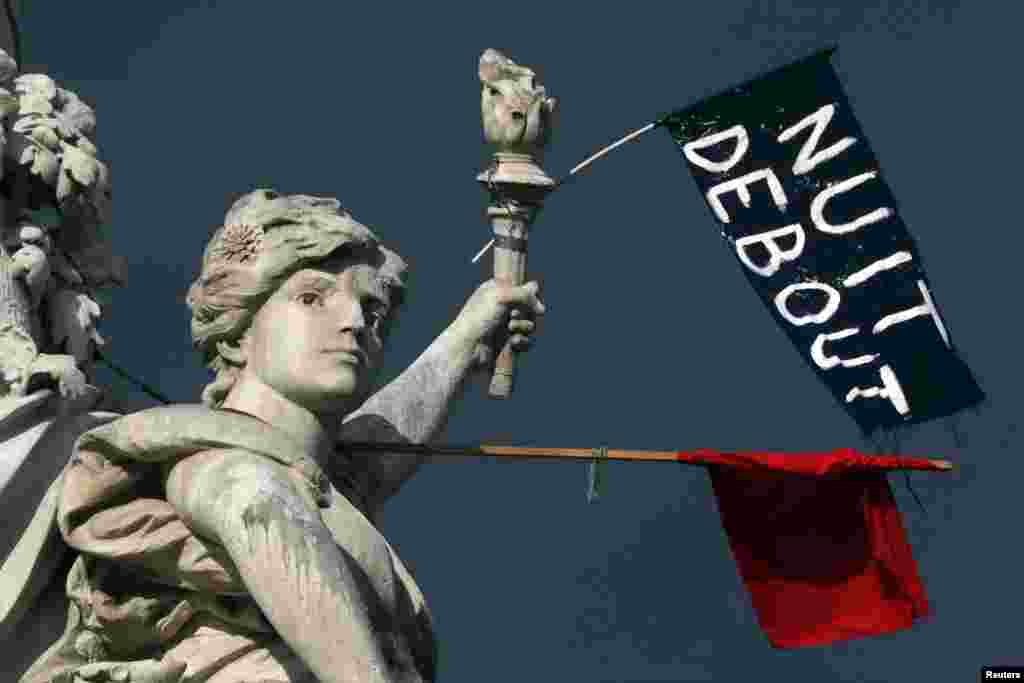 A red flag and a black one reading "Nuit Debout" (Rise Up at Night) are seen on the Place de la Republique in Paris, France, during a social media-driven movement against a labor law proposal.