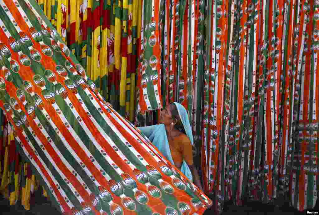 A worker pulls a roll of flags of India&#39;s ruling Congress party, kept for drying at a flag manufacturing factory, ahead of the 2014 general elections in the western Indian city of Ahmedabad.