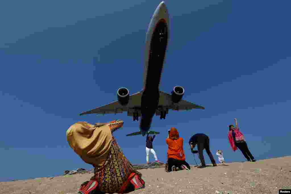 Tourists at Mai Khao Beach take pictures of a plane approaching the Phuket International Airport in Phuket, Thailand.