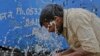 FILE - An Indian worker splashes water on his face as he tries to cool himself on a hot summer day in Allahabad, India.