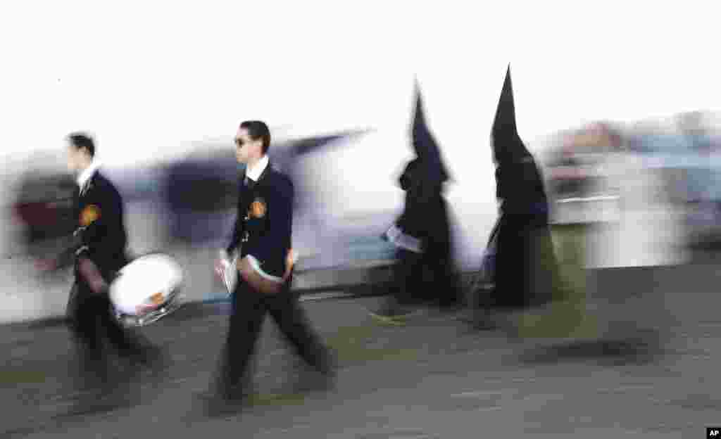 Hooded penitents from &quot;Los Dolores&quot; brotherhood walk to the church prior of the Holy Week procession in Cordoba, Spain. Hundreds of processions take place throughout Spain during the Easter Holy Week.