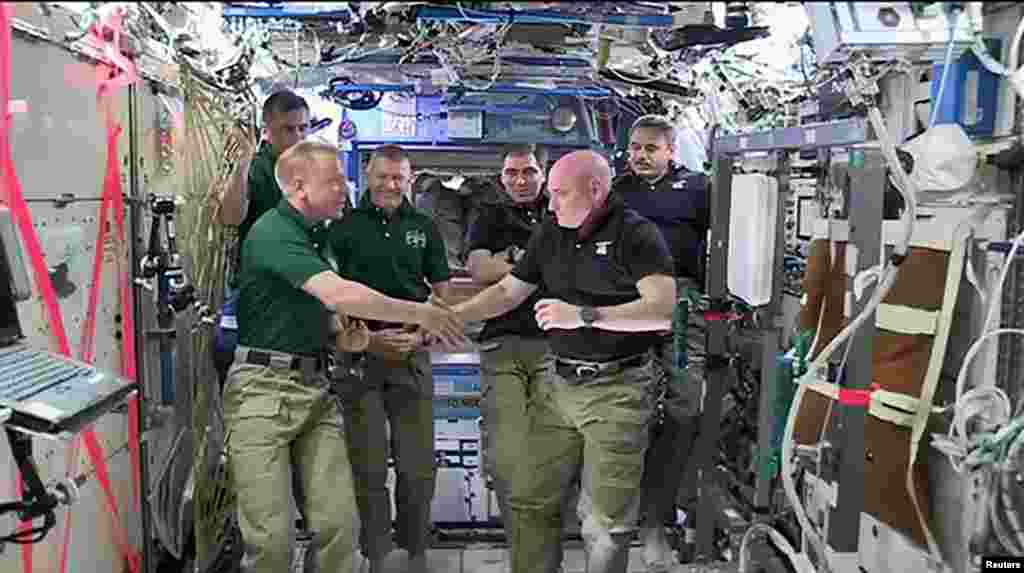 NASA astronauts Scott Kelly (R) and Tim Kopra shake hands as Kelly turns over command of the International Space Station to Kopra, Fe. 29, 2016. Kelly and Russian cosmonaut Mikhail Kornienko will land March 1 after spending a total of 340 days in space. (Credit: NASA)