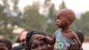 FILE - A woman holds a child on her shoulders in an internally displaced persons camp outside the town of Bunia, in Ituri province, June 21, 2019.