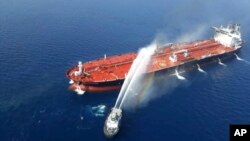 An Iranian navy boat sprays water to extinguish a fire on an oil tanker in the sea of Oman, June 13, 2019.