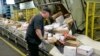 FILE - Steve Robino arranges packages on a conveyor belt at the main post office in Omaha, Neb., Dec. 14, 2017.