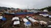 FILE - Typhoon survivors living in temporary shelters are seen near ships that ran aground, nearly 100 days after super Typhoon Haiyan devastated Tacloban city in central Philippines.