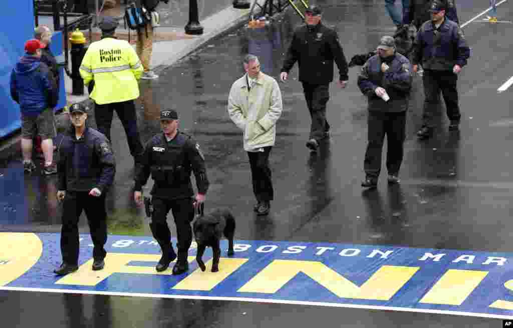 Petugas keamanan berjalan melintasi garis finish Maraton Boston sebelum acara penghargaan bagi para anggota keluarga dan penyintas pemboman Maraton Boston di Jalan Boylston (15/4). (AP/Elise Amendola)